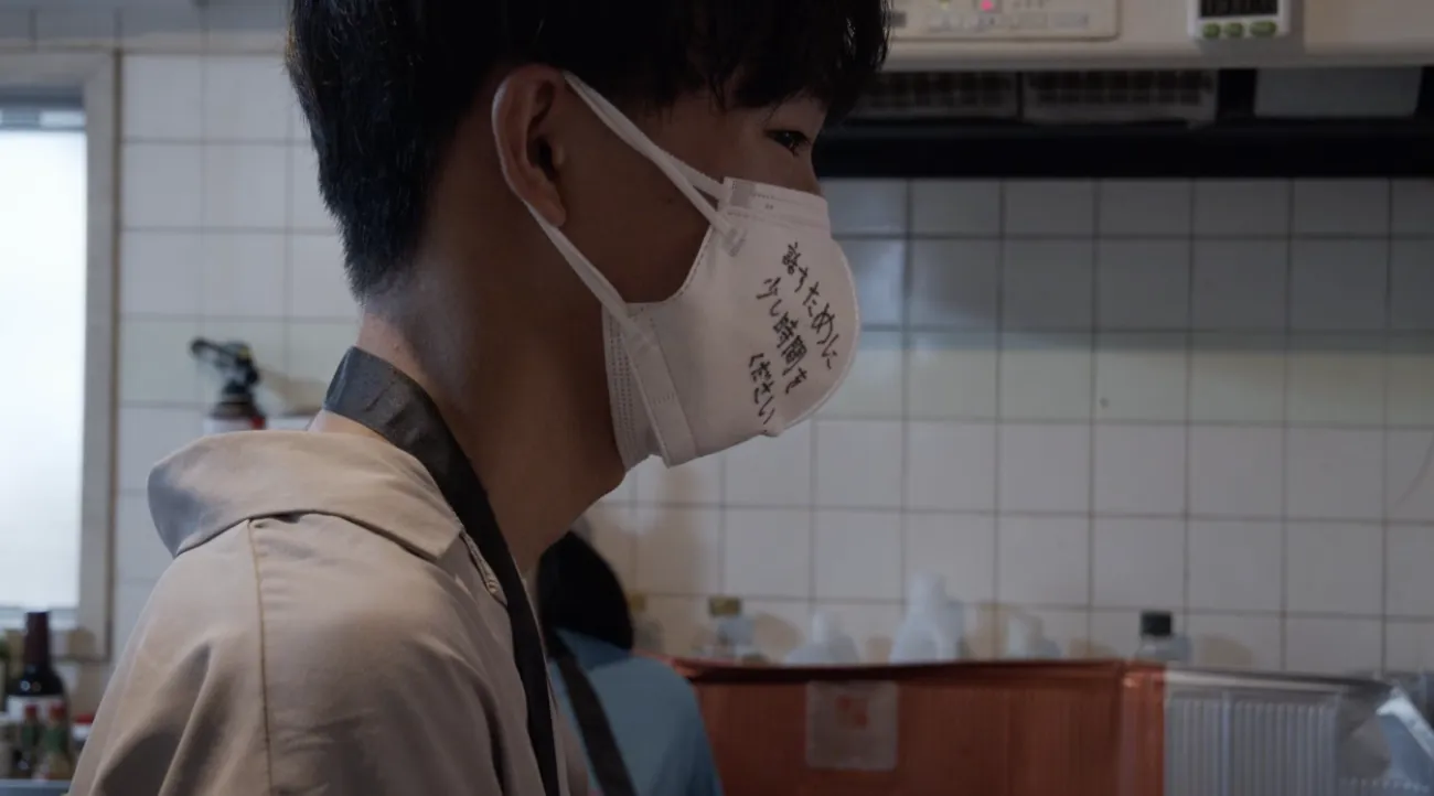 「話すために少し時間をください」と書かれたマスク